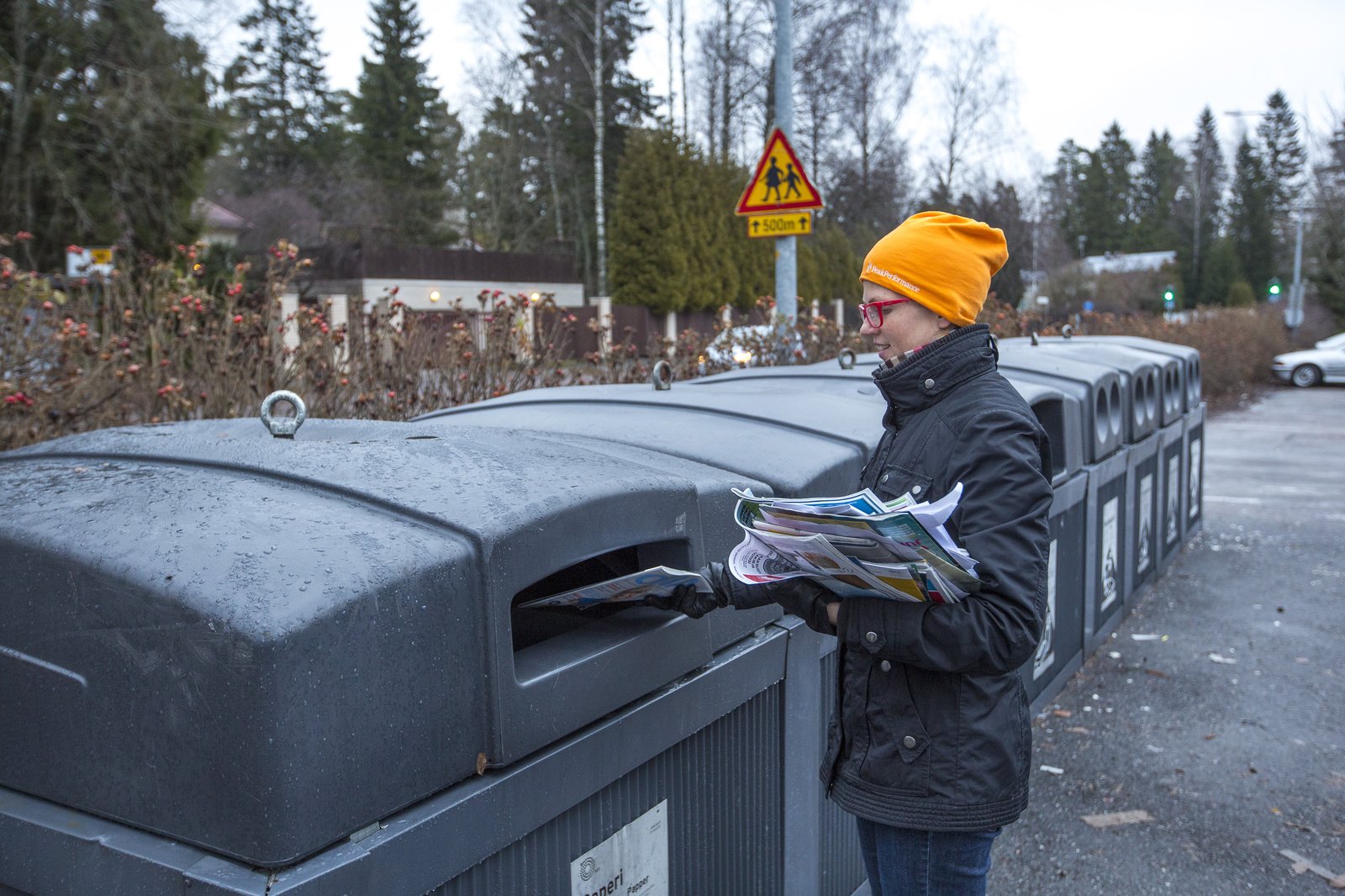 Henkilö laittaa lehtiä paperinkeräykseen.