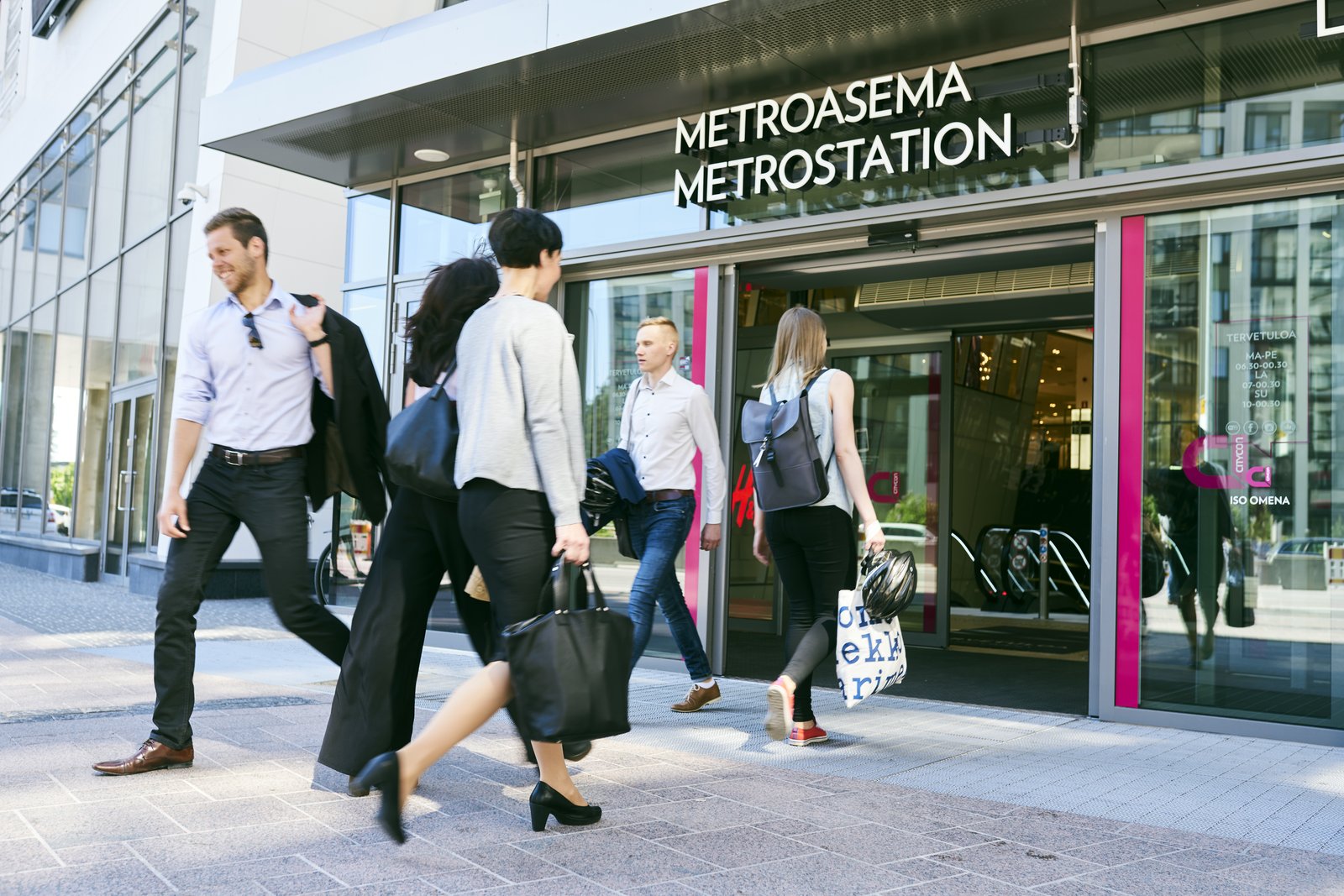 Ihmisiä kävelee sisään ja ulos metroaseman ulko-ovista.