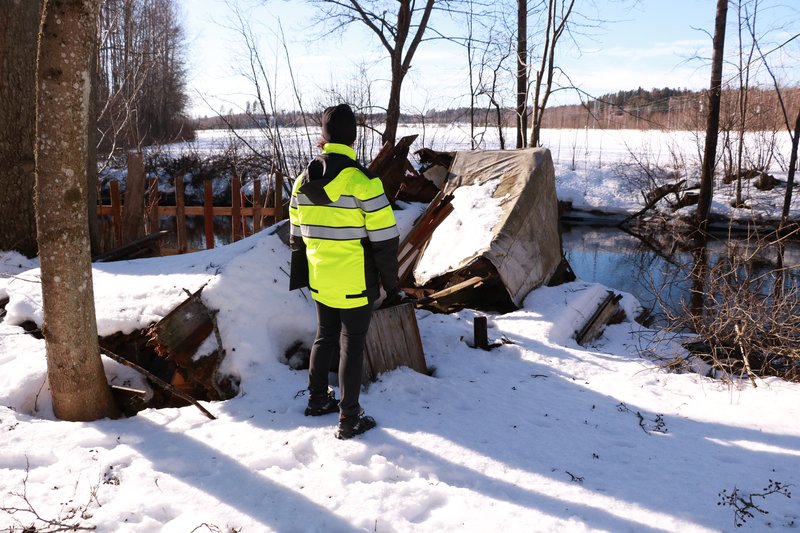 Ympäristötarkastaja huomiotakissa lumisella pihalla.