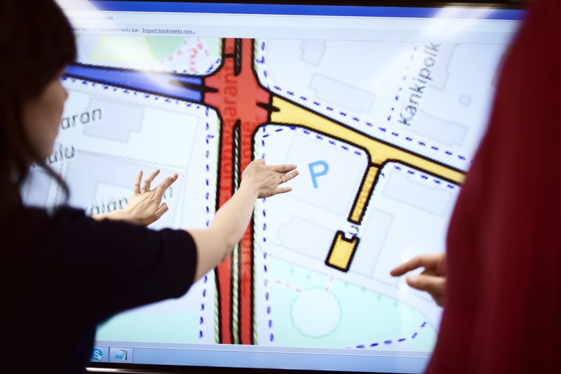 Kaksi ihmistä tarkastelee kaavakarttaa suurelta kosketusnäytöltä.