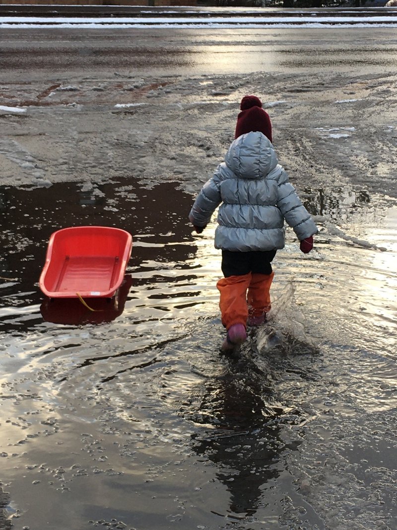 Pieni lapsi ja pulkka sohjoisessa lätäkössä.