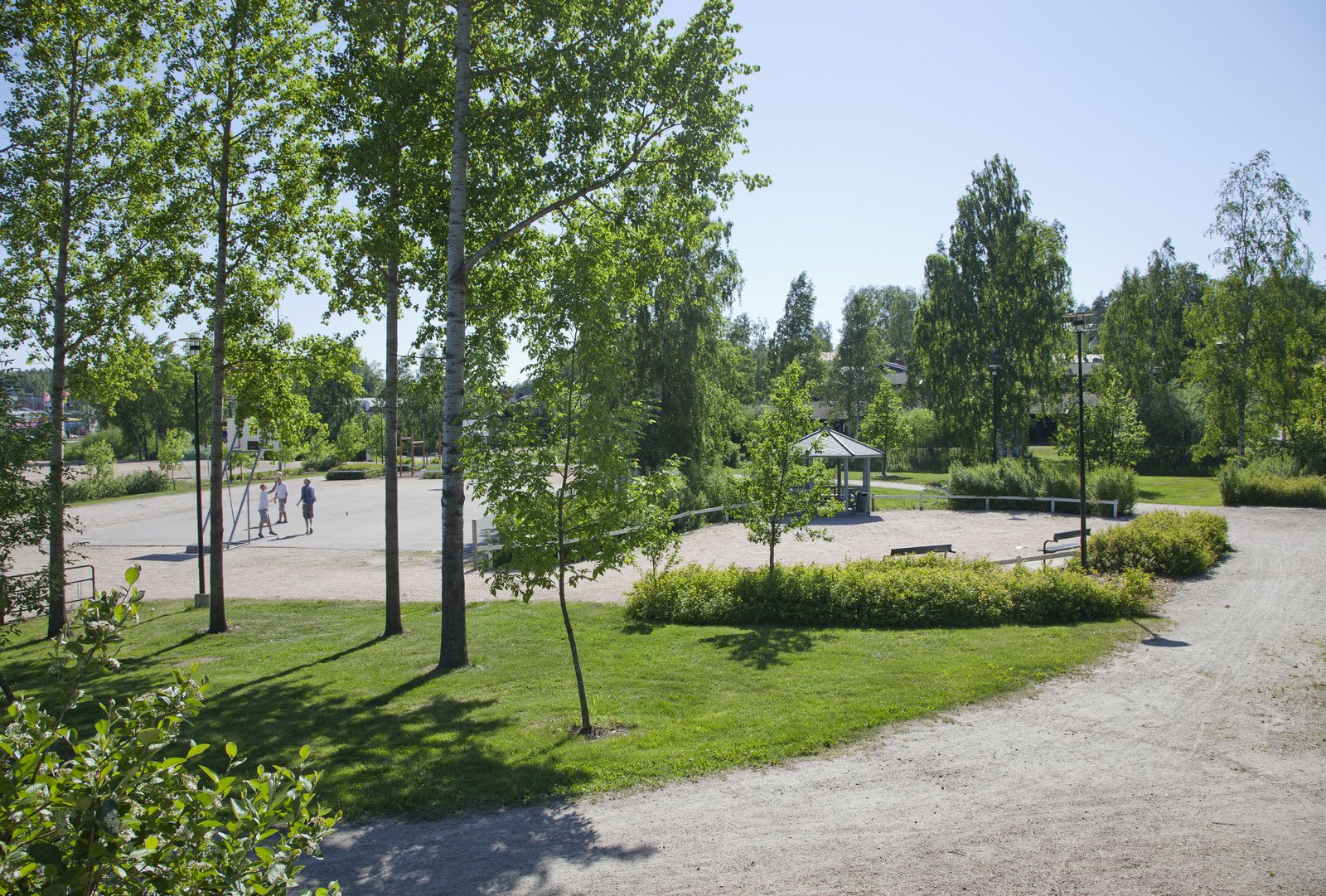 Nuoria pelaamassa jalkapalloa Matinniityn puistossa aurinkoisena kesäpäivänä.